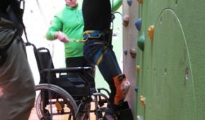 Rollstuhlfahrer klettert an einer Kletterwand
