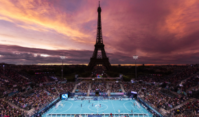 Der Eiffelturm im Sonnenuntergang bei den Paralympics in Paris. Vor dem Eiffelturm läuft ein Blindenfußballspiel.