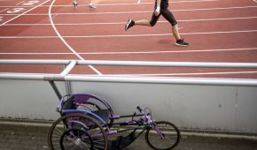 Symbolbild für den Para Sport. Ein Rollstuhl steht neben einer Leichtathletik-Laufbahn