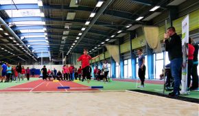 Das Foto zeigt einen jungen Sportler beim Weitsprung in eine Sandgrube