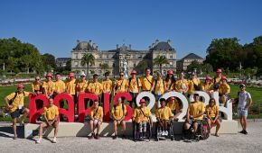 Gruppenfoto der Teilnehmer*innen des paralympischen Jugendlagers vor einem großen Paris 2024 Schriftzug