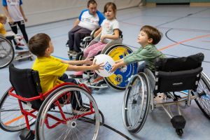 Sportwoche für Alle 2026: Kinder im Rollstuhl spielen in einer Turnhalle mit einem Ball