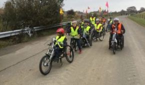 Kinder und Jugendliche fahren mit ihren Handbikes hintereinander auf einer Straße