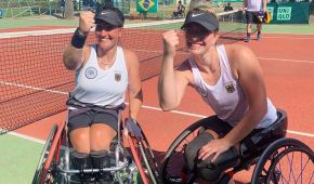 Katharina Krüger und Britta Wend jubelnd in ihren Rollstühlen. Im Hintergrund ist der Tennisplatz zu sehen.