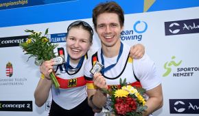 Hermine Krumbein und Jan Helmich halten ihre Silbermedaillen und zwei Blumensträuße jubelnd in die Kamera