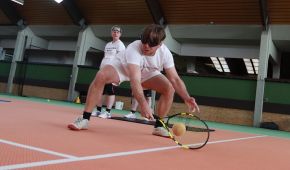 Ein blinder Tennisspieler beugt sich nach vorne und spielt den Ball