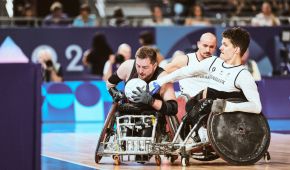 Marco Herbst versucht sich hier gegen die Verteidigung der Dänen durchzusetzen. Dafür hat er den Ball in seiner linken Hand und drückt ihn gegen seine Brust. Ein dänischer Gegenspieler versucht, ihm den Ball abzunehmen.