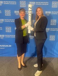Katja Kliewer und Mareike Miller halten gemeinsam eine Paralympische Fackel