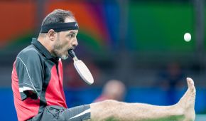Ein Tischtennisspieler ohne Arme, der den Schläger beim Aufschlag im Mund hält