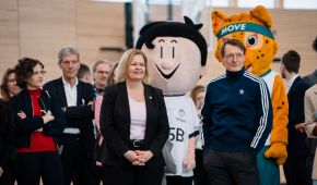 Nancy Faeser und Prof. Dr. Karl Lauterbach stehend mit Maskottchen