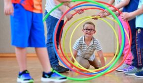 Kleiner Junge klettert durch bunte Ringe