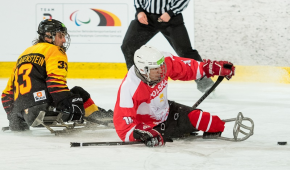Ein Para Eishockeyspieler aus Deutschland kämpft mit seinem Gegenspieler aus Polen um den Puck