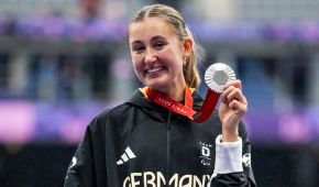 Nele Moos zeigt ihre Silbermedaille und lächelt in die Kamera.