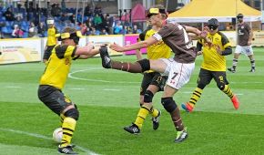 Ein Spieler von St. Pauli schießt den Ball, ein Gegenspieler von Borussia Dortmund versucht, den Ball abzuwehren