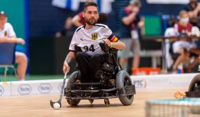Ein deutscher Powerchair Hockey-Spieler mit seinem Schläger und dem Ball