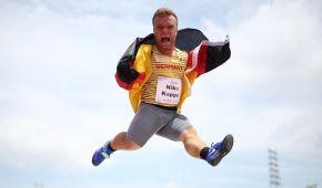 Niko Kappel springt freudig in die Höhe, hält dabei die Deutschlandfahne hinter sich - im Hintergrund das Stadion