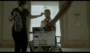 Screenshot des Trailers, im Hintergrund ist Maurice Schmidt in seinem Rollstuhl zu sehen, im Vordergrund eine Filmklappe