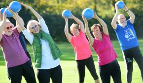 Rehasportgruppe bei einer Übung mit Ball über dem Kopf