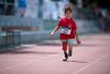 Ein Mädchen mit einer Beinprothese läuft mit freudigem Ausdruck über die Tartanbahn